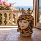 Handcrafted Teste di Moro ceramic vase with crown, vibrant colors, set against a scenic balcony view.