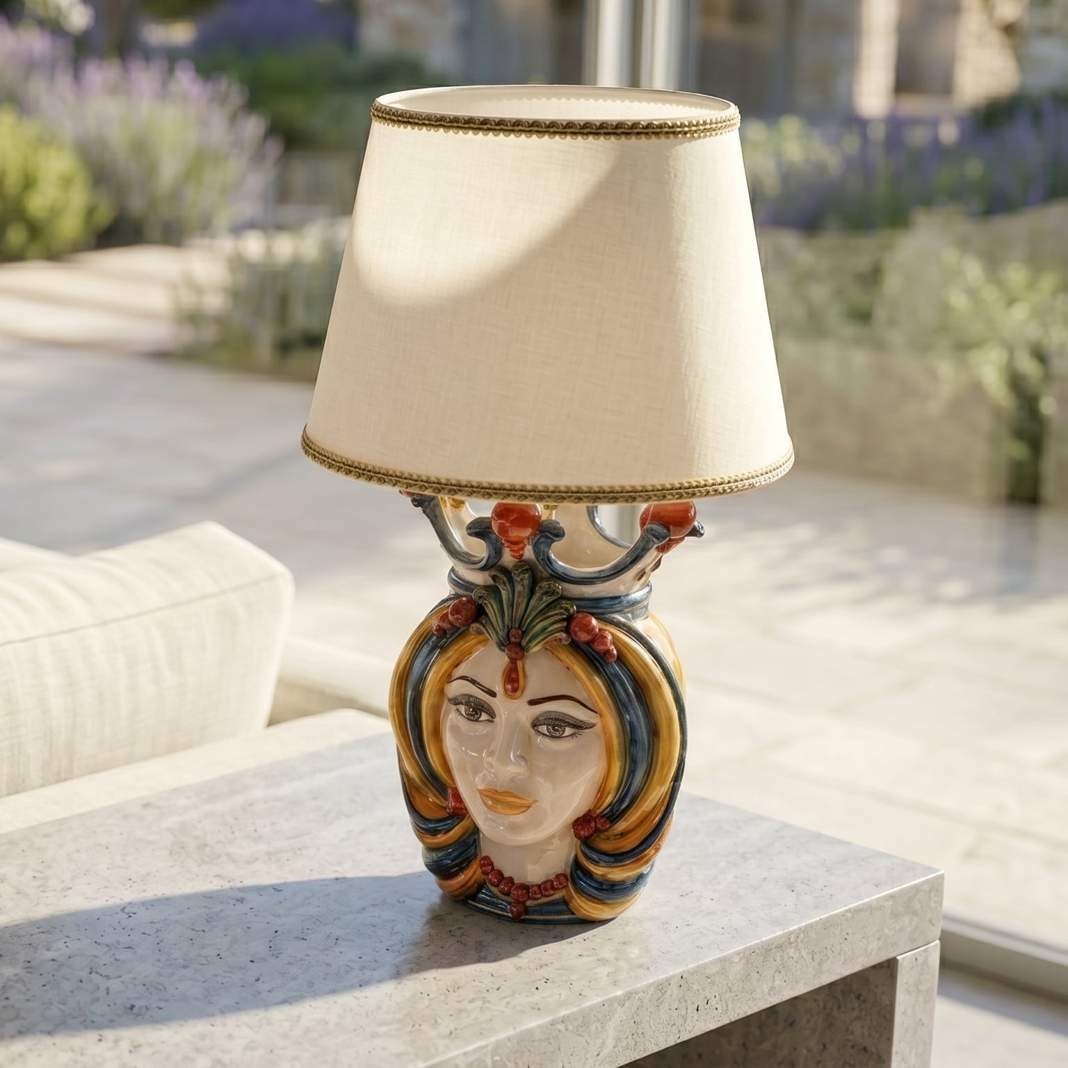 Handcrafted Teste di Moro table lamp with colorful ceramic face, beige shade, on outdoor stone table