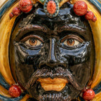 Handcrafted Teste di Moro ceramic face with vibrant glaze, detailed eyes, and ornate red bead crown.