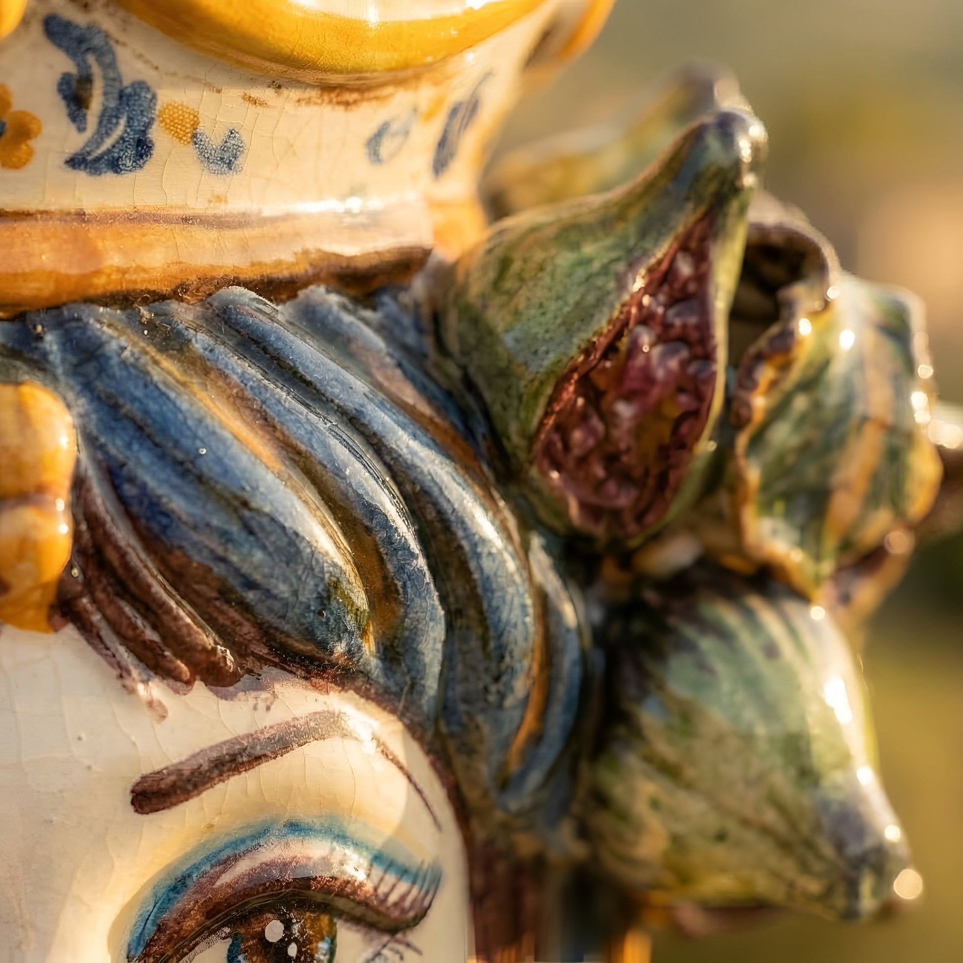 Hand-painted ceramic Teste di Moro with vibrant blue, green, and yellow glaze, showcasing intricate floral details and traditional craftsmanship.