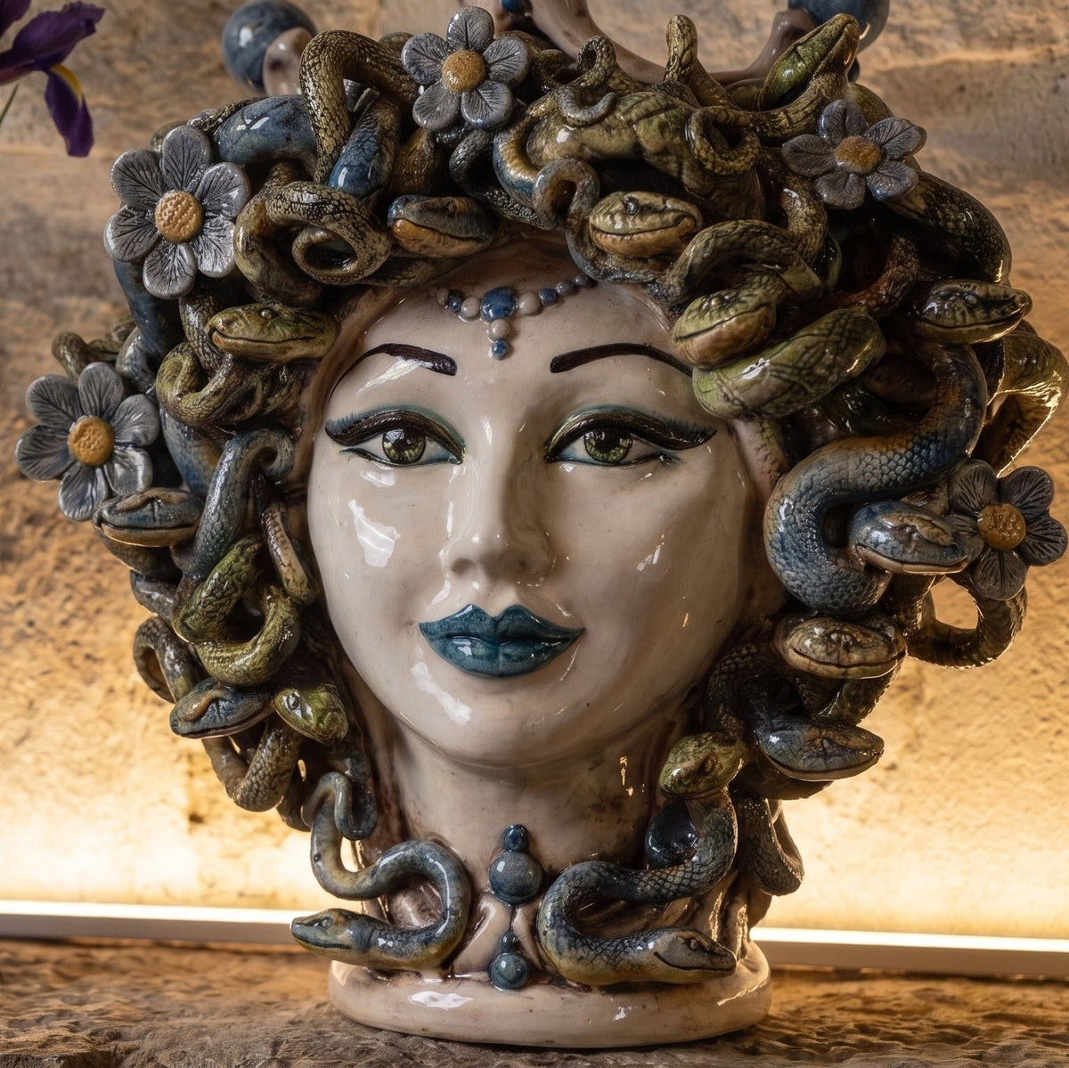 Detail des Medusenkopfs mit Blumen: Perlmuttgesicht, blaue Lippen und Schlangenhaar