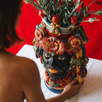 Handcrafted Teste di Moro vase with vibrant floral crown, holding olive branches, showcasing Sicilian ceramic artistry