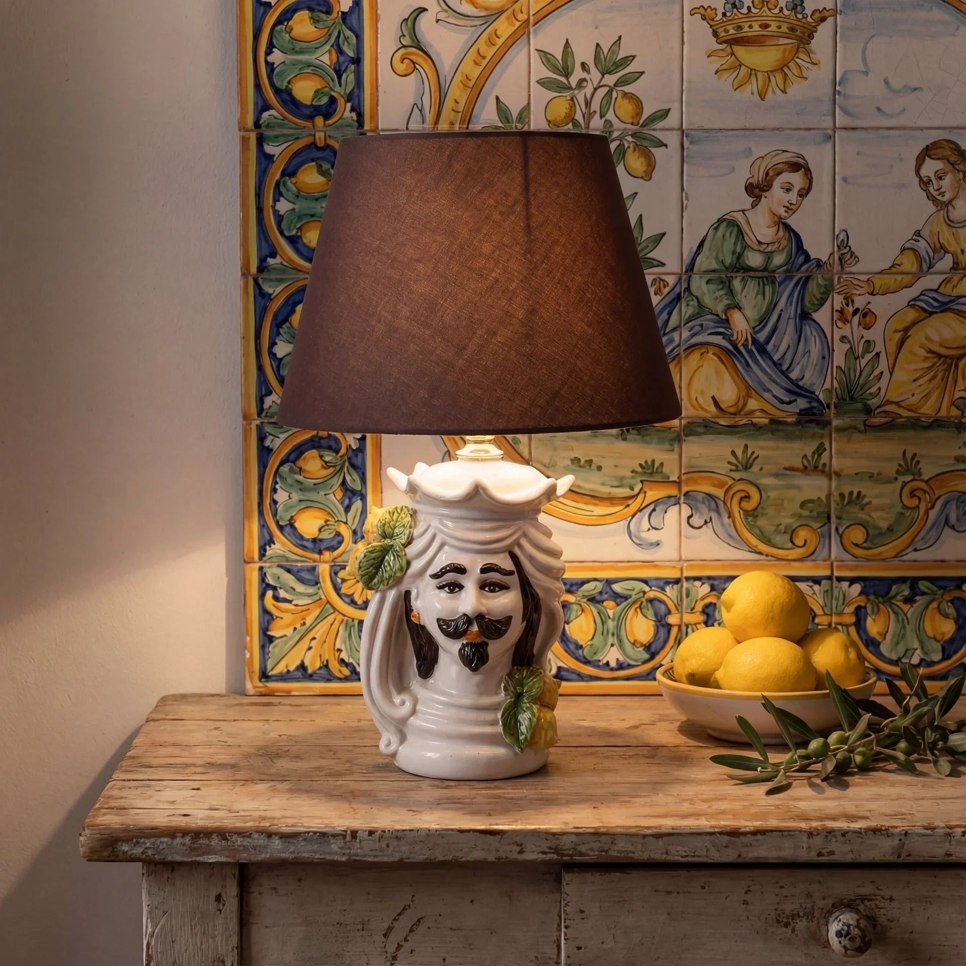 Handmade ceramic Teste di Moro lamp with mustache, lemon accents, and brown shade on rustic table