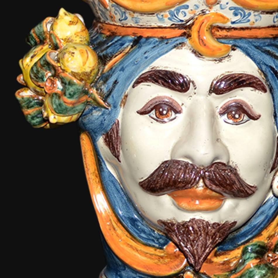 Handcrafted Teste di Moro ceramic face with vibrant blue turban, mustache, and floral details, blending tradition and modern design.