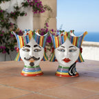 Colorful hand-painted Teste di Moro ceramic vases with striped crowns, set outdoors on terrace