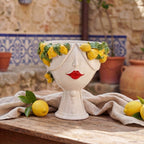 Handmade ceramic Testa di Moro with lemon wreath, red lips, on rustic table with lemons