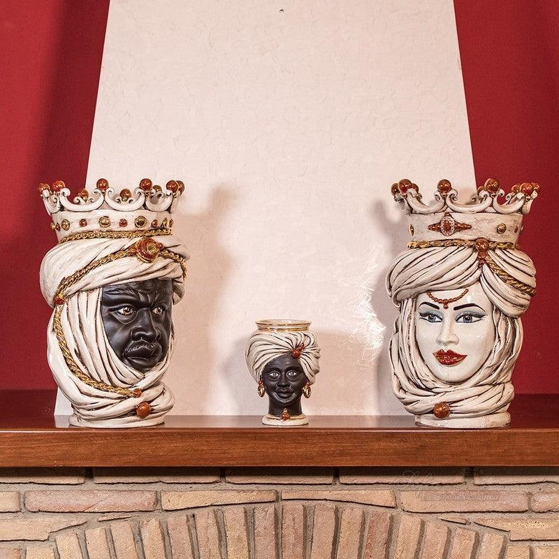 Handcrafted Teste di Moro ceramic statues with crowns and turbans, displayed on a wooden mantel.