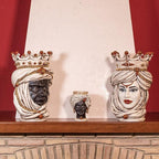 Handcrafted Teste di Moro ceramic statues with crowns and turbans, displayed on a wooden mantel.