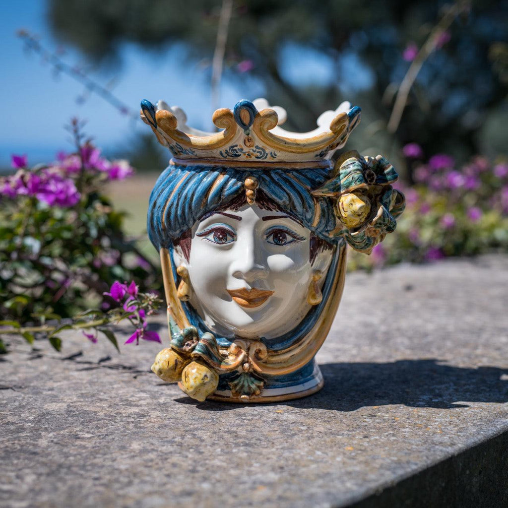 Handcrafted Teste di Moro ceramic vase with crown, blue hair, floral details, outdoor garden setting
