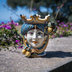 Handcrafted Teste di Moro ceramic vase with crown, blue hair, floral details, outdoor garden setting