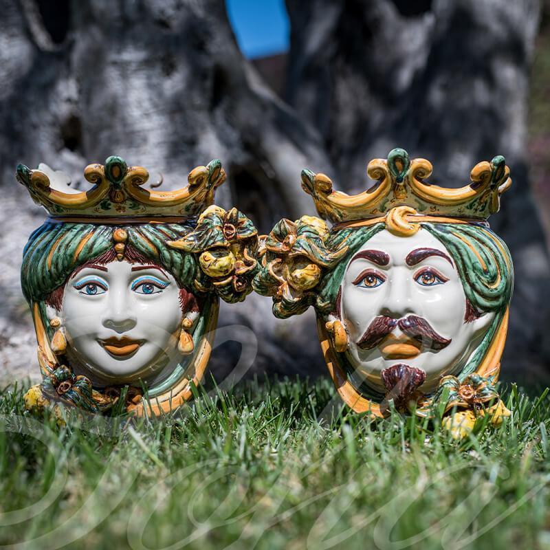 Handcrafted Teste di Moro ceramic faces with crowns, vibrant colors, set on grass — traditional Sicilian art