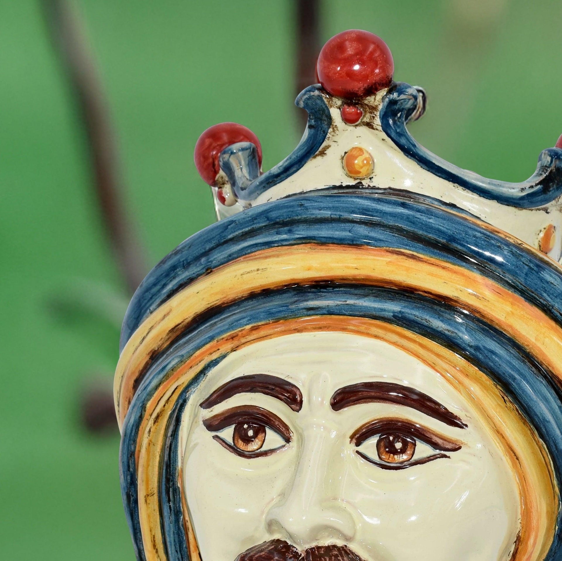 Handmade Teste di Moro ceramic face with blue crown, red accents, and expressive eyes