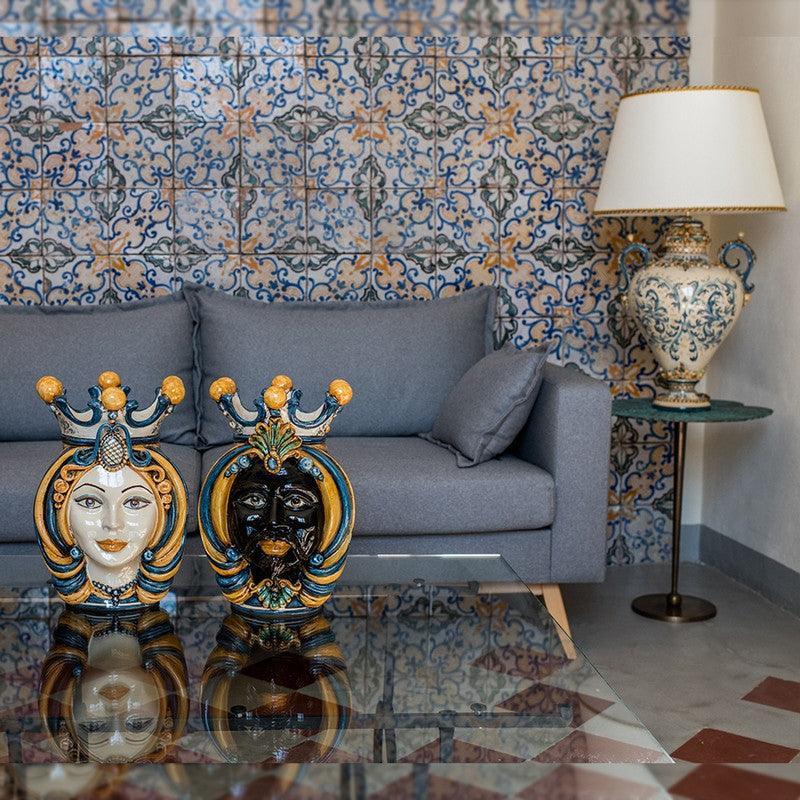 Handmade Teste di Moro ceramic sculptures with crowns, displayed on glass table in modern living room
