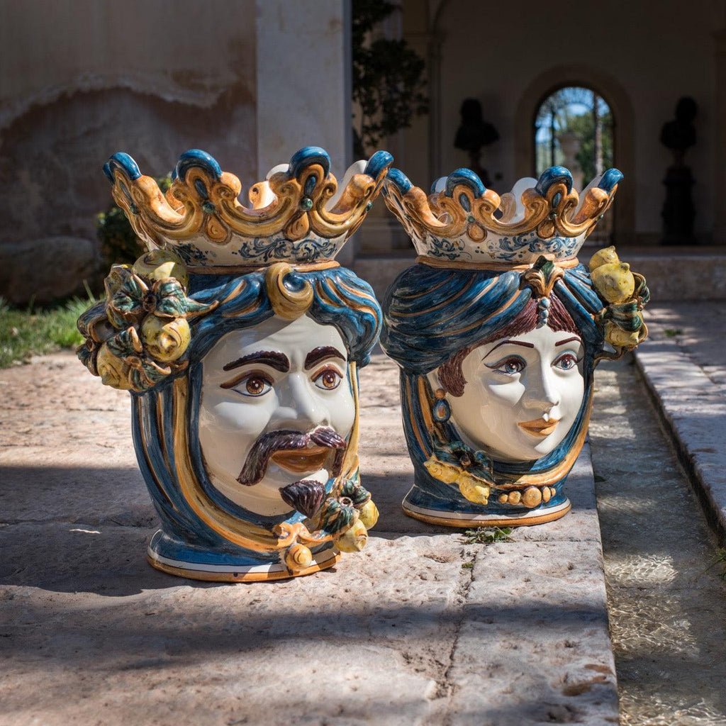Handmade Teste di Moro ceramic vases with crowned male and female faces, vibrant blue and gold details, outdoor display