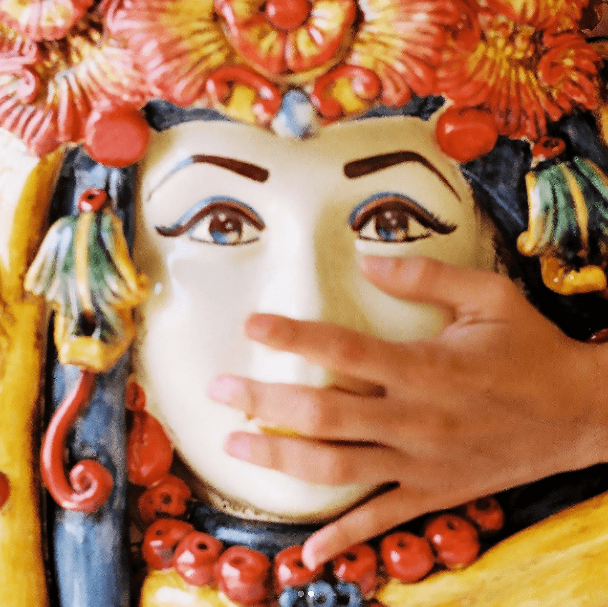 Hand touching colorful ceramic Testa di Moro with floral crown and vibrant details