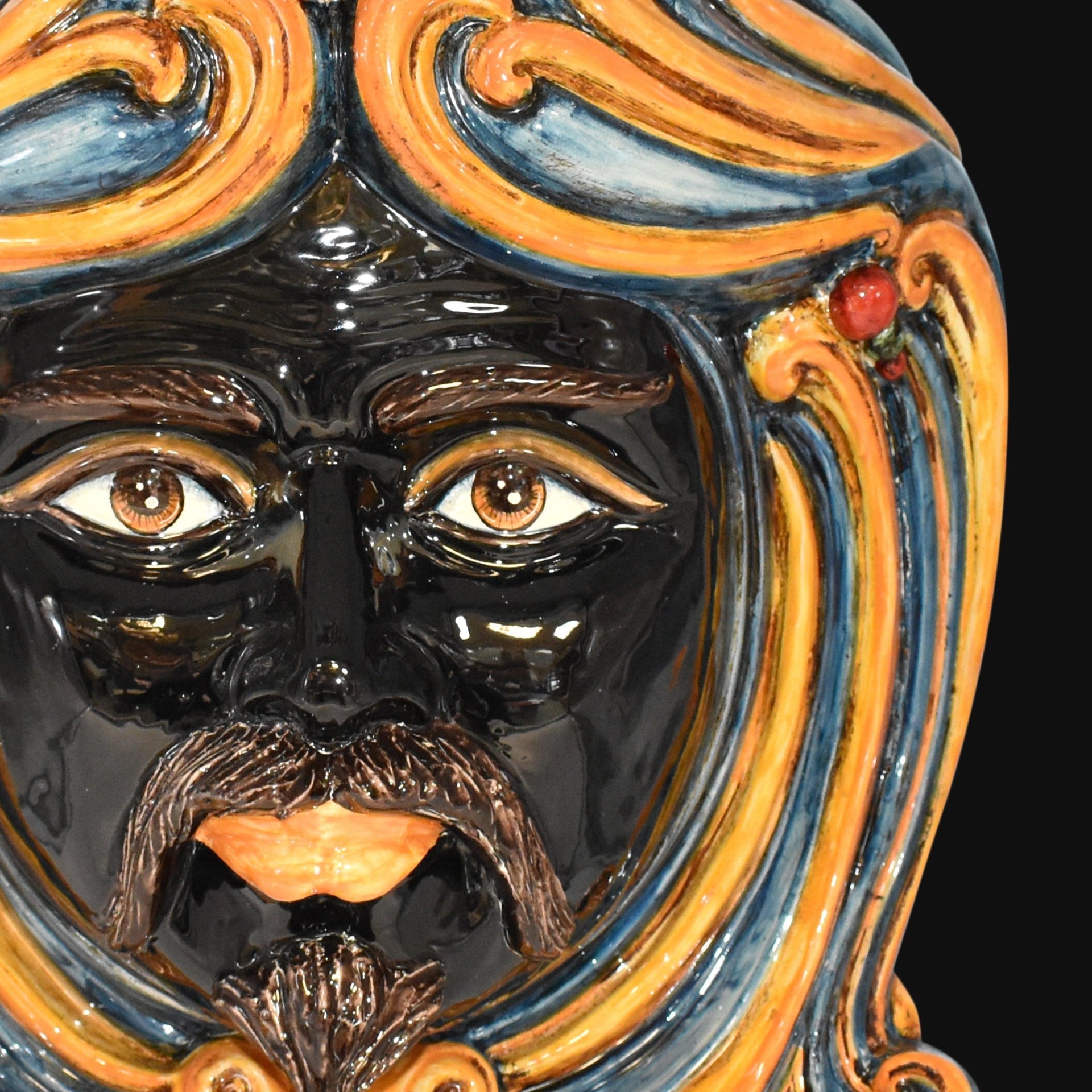 Handcrafted Teste di Moro ceramic face with vibrant blue and orange swirls, glossy finish, and expressive eyes.